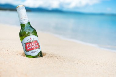  Bir şişe Stella Artois kısmen kumsalda gömülü..