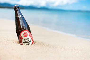 Bir şişe Red Horse Ekstra Sert Bira kısmen kumsalda gömülü..