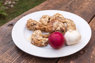 Kremalı Tuzlu Yumurta Kanatları, bir baş sarımsak ve tuzlu yumurta, kırsal bir bankta beyaz bir tabakta..