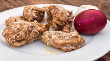 Kremalı Tuzlu Yumurta Kanatları, bir baş sarımsak ve tuzlu yumurta, kırsal bir bankta beyaz bir tabakta..