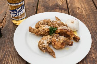 Filipinler - Eylül 2020 Sarımsaklı Parmesan Kanatları ve San Miguel Light Birası açık hava bahçesinde bir masada.