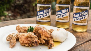 Filipinler - Eylül 2020 Sarımsaklı Parmesan Kanatları ve San Miguel Light biraları açık hava bahçesinde bir masada.