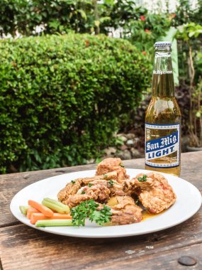 Filipinler - Eylül 2020 Sarımsaklı Parmesan Kanatları ve San Miguel Light Birası açık hava bahçesinde bir masada.