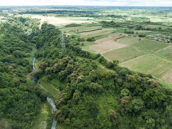 Aerial of an electric pylons running along a river gorge and undeveloped farmland in Dasmarinas Cavite.