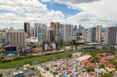 Metro Manila, Philippines - July 2020: Condominiums in Mandaluyong City loom over the Pasig River and slum areas in Makati. clipart