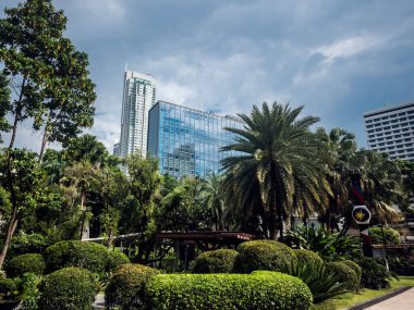 Makati, Metro Manila, Filipinler - Eylül 2020: Yeşil kuşak kompleksi içinde arka planda Raffles Makati görünen bir peyzaj parkı.