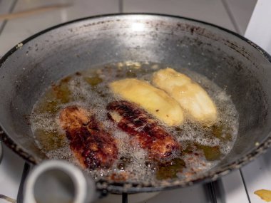 Frying Banana Cue on a large pan on a stove. It is a popular snack food or street food in the Philippines. clipart