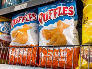 Manila, Philippines - Sept 2020: Cheetos is a brand of ruffled (crinkle-cut) potato chips made by Frito-Lay. Cheddar and Sour cream flavor variant on an aisle at a supermarket. clipart