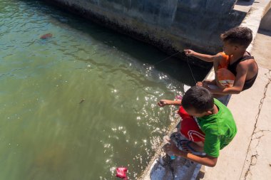 Ubay, Bohol - Jan 2016: 2 erkek çocuk balıkçılık için balıkçı halatını kullanarak limanda yiyecek yakalamaya çalışıyor.