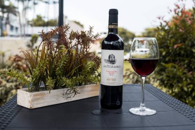 Manila, Filipinler - Ekim 2020: Al fresco bölgesinde siyah bir masada şarap kadehi ve şişe. Şarap İspanya 'dan Altozano Tempranillo Syrah.