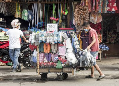 Zapote Market, Las Pinas, Metro Manila - Ekim 2020: Geçici el arabası ile yüz maskeli genç bir adam, yerel olarak Kariton olarak bilinir, terlik satıyor