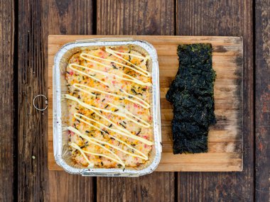 Ahşap tepside Nori Seaweed 'le servis edilen fırınlanmış suşi manzarası. Açık hava restoranı..