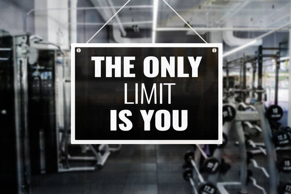 A signage with words - The Only Limit is you - in front of a gym or fitness center. Motivational quote. Yellow and black design.