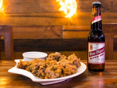 Manila, Philippines - Oct 2020 - San Miguel Super Dry Beer served with Calamares and dip as side dish. At a bar or pub.