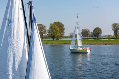North Brabant/ Hollanda - 21 Nisan 2019: Güneşli bir bahar gününde Meuse nehri üzerinde yelkenli gemiler