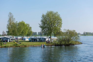 North Brabant/ Hollanda - 21 Nisan 2019: İnsanlar ilkbaharda Meuse nehri kıyısında çadırlarda ve kampçılarda dinleniyor