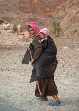 HIGH ATLAS / MOROCCO- 6 Mart 2014: Çocuklu fakir Faslı kadın yürüyüp gitti