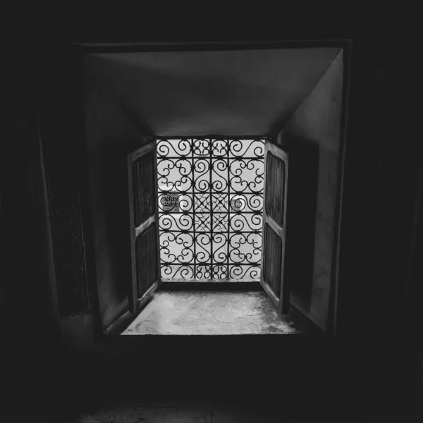 Black and white photo of a sunlit window of a Moroccan building