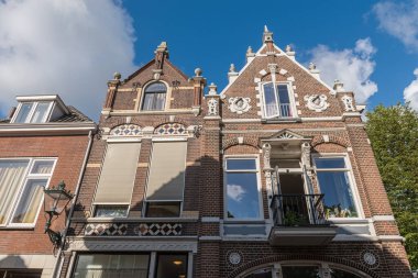 KAMPEN, OVERIJSSEL / The NETHERLANDS - 20 HAZİRAN 2020: Sabah vakti Hollanda 'daki tarihi binaların güzel cepheleri mavi gökyüzüne karşı bulutlar