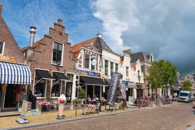 Workum, FRIESLAND / The Netherlands - 16 Temmuz 2020: Güneşli bir yaz gününde dükkanları ve kafeleri olan şehrin merkezi caddesi