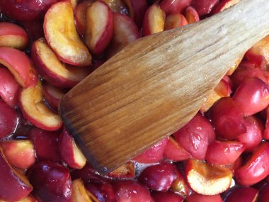 Kırmızı elma dilimlerinin arasında tahta bir kaşık var.