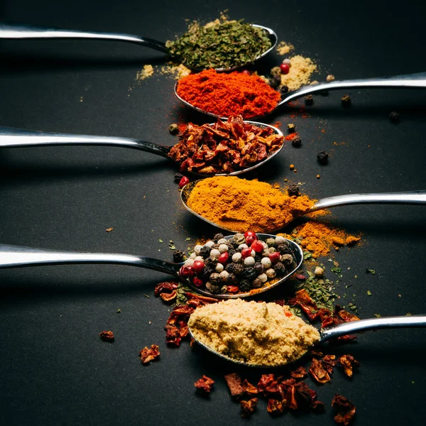 Spices on a metal spoon on a black background — Stock Photo, Image