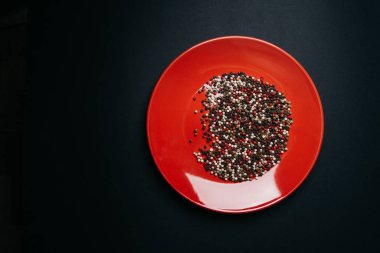 Kırmızı tabak ve koyu arkaplanda biber karışımı.