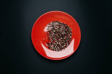 Kırmızı tabak ve koyu arkaplanda biber karışımı.