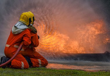 Yangın söndürücü ve hortumla yangın söndürücü kullanan iki cesur itfaiyeci ateş etmek için yüksek basınçlı su sıkan itfaiyeci tehlikeli alevlerle eğitimli itfaiyeci uzay görüntüsünü kopyalayın.