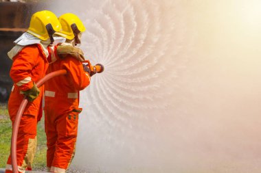 Yangın söndürücü ve hortumla yangın söndürücü kullanan iki cesur itfaiyeci ateş etmek için yüksek basınçlı su sıkan itfaiyeci tehlikeli alevlerle eğitimli itfaiyeci uzay görüntüsünü kopyalayın.