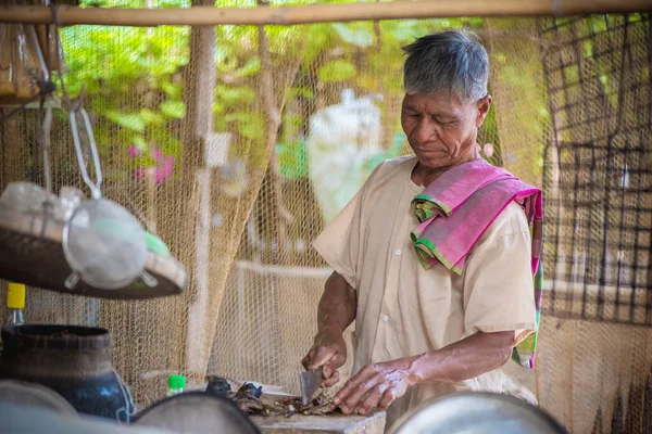 Old man with cream-colored shirts and plaid scarves in the countryside of asia is cooking, Country kitchen, Simple living in the countryside concept.