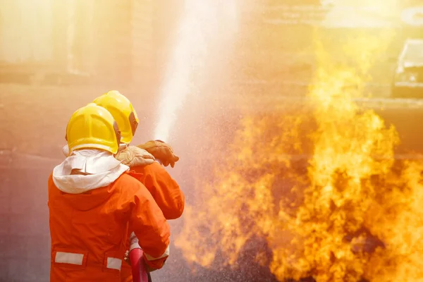 消火器と消火ホースからの水を使用して2人の勇敢な消防士 火災に高圧水を噴霧消防士 危険な炎で消防訓練 スペースイメージのコピー — ストック写真