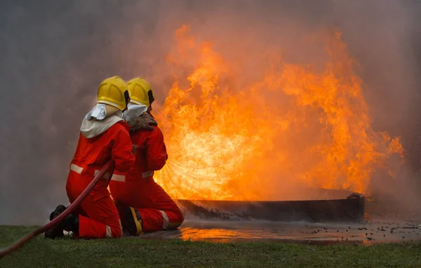 Two brave firefighter using extinguisher and water from hose for fire fighting, Firefighter spraying high pressure water to fire, Firefighter training with dangerous flames, Copy space-Image