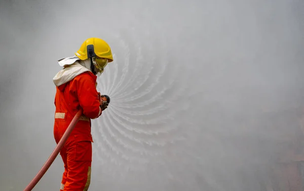 Brave firefighter using extinguisher and water from hose for fire fighting, Firefighter spraying high pressure water to fire, Firefighters training, foreground is drop of water springer-Image