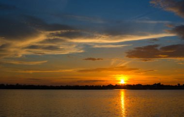 Gökyüzünde güzel bir gün batımı, gökyüzünde mavi ve turuncu güneş ışığı, gökyüzündeki bulutlar, turuncu ve denizin üzerindeki kırmızı dramatik renkler. - Görüntü