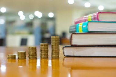 Gelir grafiği gibi altın para yığınları, farklı pozisyonlarda beş para yığını, Tayland para birimi ve bokeh arka planlı kitaplar, yatırım ve iş dünyasındaki büyüme kavramı.