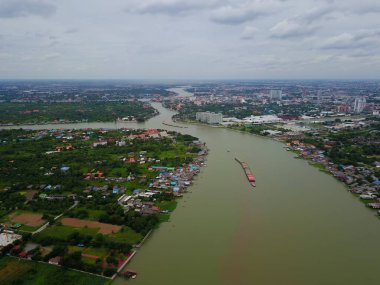 Şehir manzaralı Chao Phraya Nehri 'ndeki büyük kargo gemisinin havadan görüntüsü, yağmur mevsiminde yeşil suyu olan nehir, kopyalama alanı, Üst Manzara, Bangkok, Tayland.