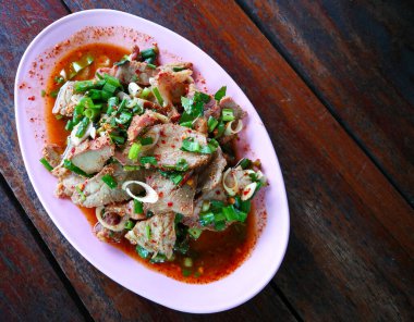 Acı biberli ve soğanlı Tayland baharatlı ve baharatlı domuz salatası, baharatlı Tayland baharatlı yemek. Tahta arka planda pembe bir tabakta Tayland yemeği..