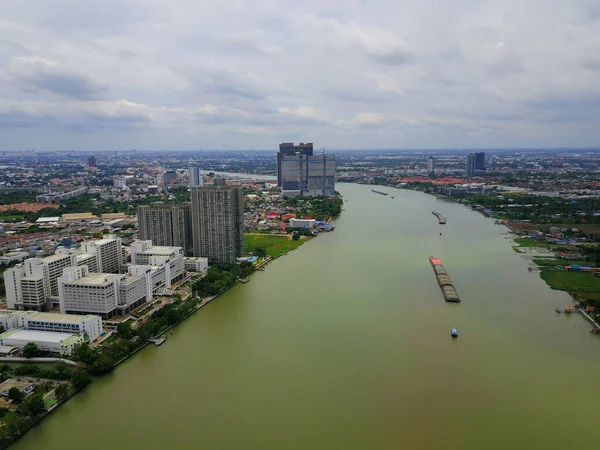Aerial view of the large cargo ship on the Chao Phraya River with cityscape, The river with green water in rainy season, Copy space, Top view, Bangkok, Thailand.