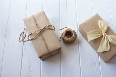Beyaz ahşap masa üzerinde el sanatları kağıdına sarılmış hediye.