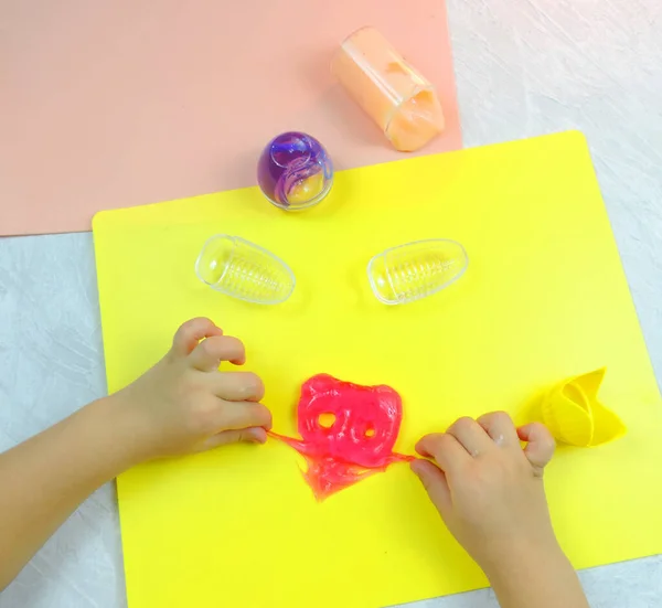 child's hands made funny slime heart  ,  yellow background