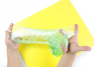         Çocuk elleri ve yeşil sümük, çekiç sümüğü, sarı arka plan.       