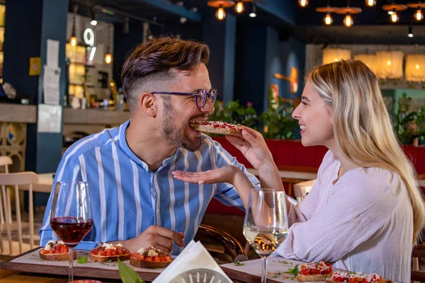  Güzel bir restoranda birbirini bruschetta ile besleyen mutlu, genç ve romantik bir çift..