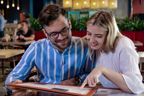 Güzel, romantik bir restoranda yemek sipariş eden genç ve mutlu bir çift. Güzel yemek konsepti.