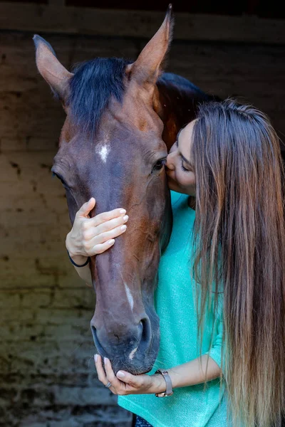 Красивая Юная Брюнетка Присматривает Своей Лошадью Конюшне Целуя Жеребца Любовью — стоковое фото