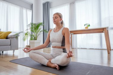  Güzel, aktif, genç bir kadın evde egzersiz yapıyor. Yoga yaparken nilüfer çiçeği pozu veriyorum. Sağlıklı yaşam tarzı ve spor konsepti. Bir dizi egzersiz pozu.