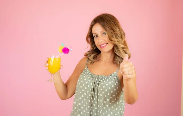 Woman with a cocktail on pink background