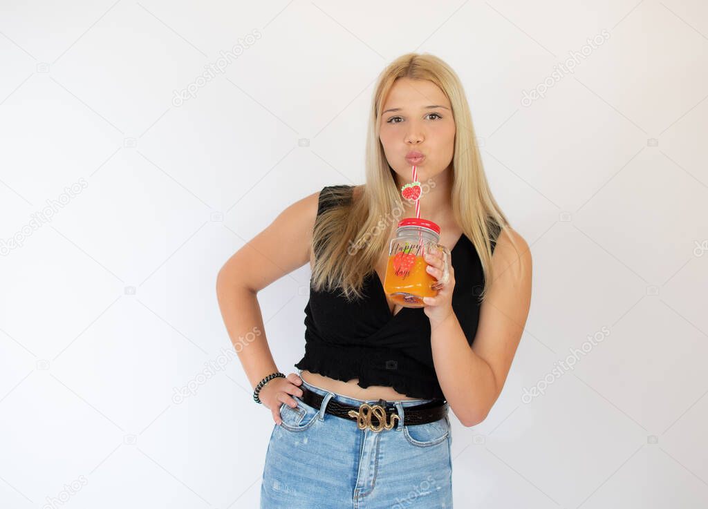 Beautiful blonde girl in black shirt drinking a fruit juice