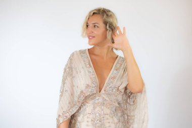 Beyaz arka planda, parti elbisesi içinde gülümseyen güzel sarışın kadın.