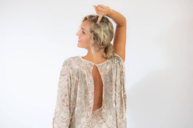 Beyaz arka planda, parti elbisesi içinde gülümseyen güzel sarışın kadın.